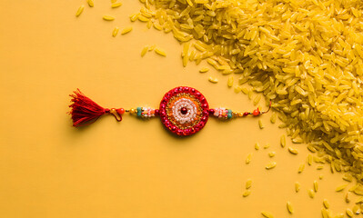 Obraz premium Raksha Bandhan, an Indian holiday adorned with intricate Rakhi patterns and yellow backgrounds featuring rice grains. It's a cherished traditional wristband representing the bond between sisters and b