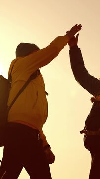A man in a yellow jacket walks against a bright backdrop. The man is silhouetted, showcasing his backpack and determination in the fading sunlight.