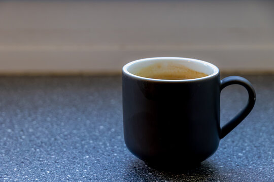 A black ceramic mug filled with fresh coffee on windowsill in soft natural light through window, Ideas for cozy morning cafe or daily routine concepts with copy space, Barista and beverage background.