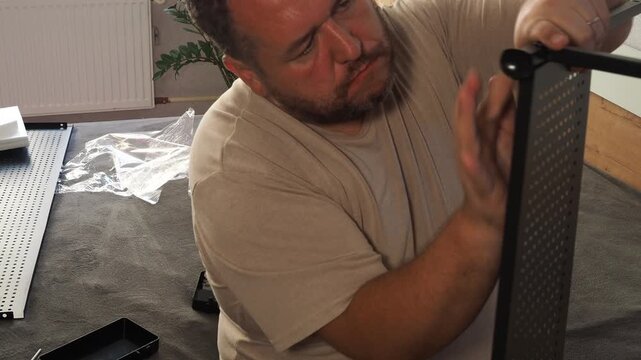 The man is repairing the shelf. Worker assembling furniture