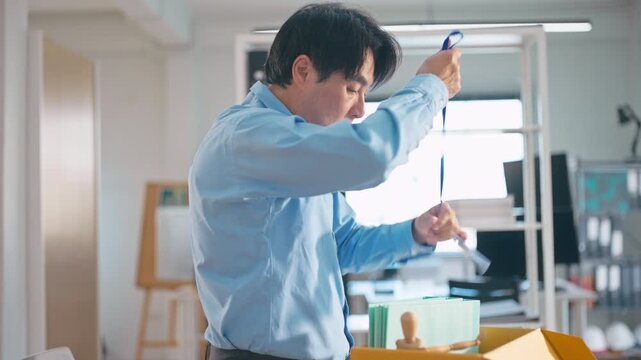 Asian businessman packing personal belongings in box after being laid off from job