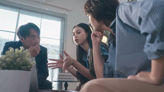 Asian Business Team of Three Discussing Project on Laptop in Office.