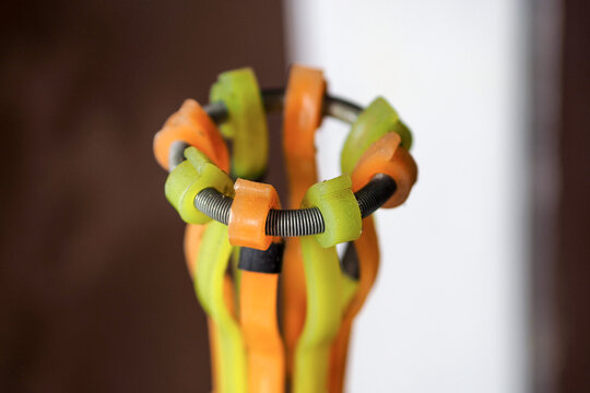 lose-up shot of a light bulb changer head with flexible orange and green plastic grippers and a metal ring spring mechanism.