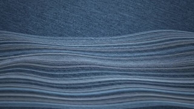 Abstract blue fabric textile with flowing horizontal wavy lines and textured detailed background