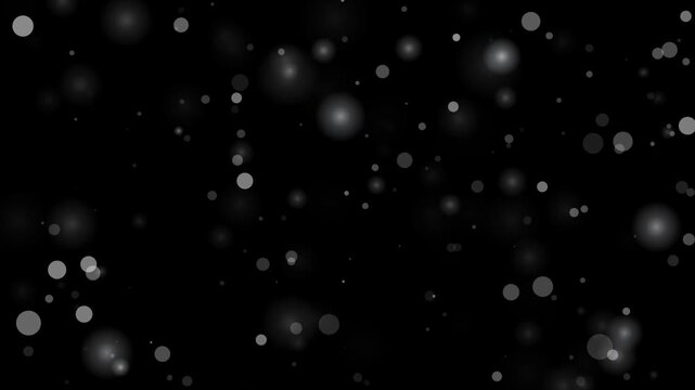 Abstract white glowing bokeh and light particles floating gently across a dark black background in a continuous looping motion.