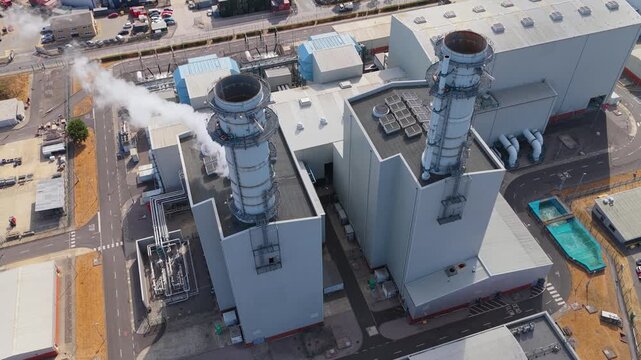 Industrial Power Plant Operations With Smoke Emitting From Tall Chimney Stacks