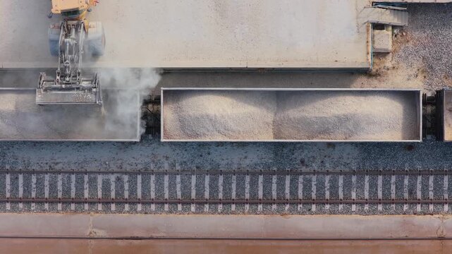 Heavy Loader Machine Filling Industrial Gravel Into Train Carriages at a Quarry