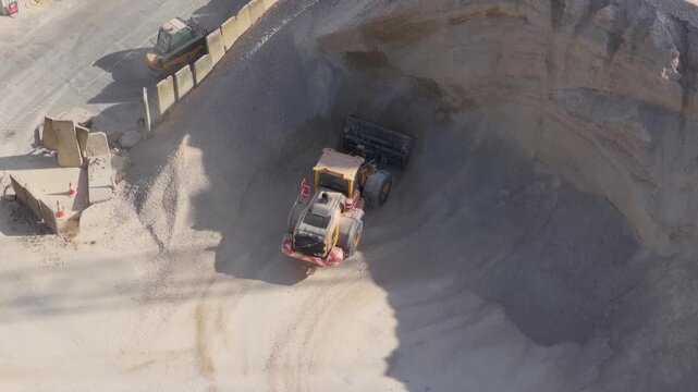 Wheel Loader Moving Gravel Into a Train Car at a Quarry During the Daytime