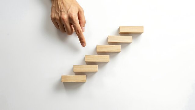 Climbing the ladder of success hand reaching for wooden blocks growth and achievement