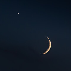 Narrow crescent moon in dark sky with lonely star © Igor