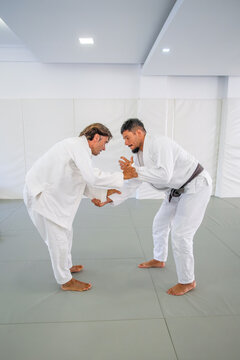 In Brazilian jiu jitsu, two black belts square off on the tatami and fight for sleeve and collar grips in a standing takedown drill