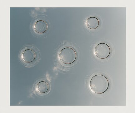 Brass gold pipe rings floating on calm pewter grey water, a minimal study of home heating parts for winter energy and maintenance concepts