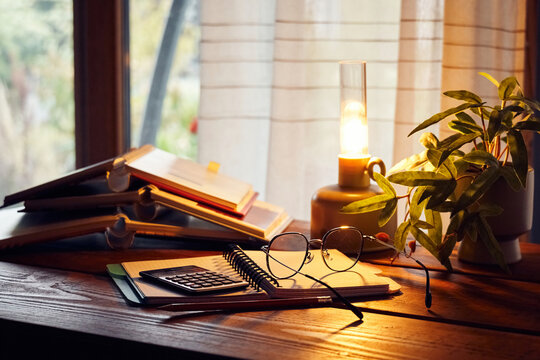 Warm desk setting with books, plants, and tools for study or work