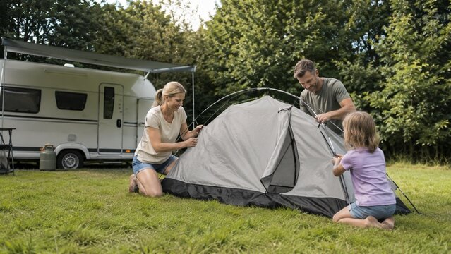 Familie baut gemeinsam ein Zelt auf dem Campingplatz auf