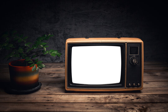 Vintage yellow old television with a blank white screen, placed on table near a potted plant in a dark room, cut out screen