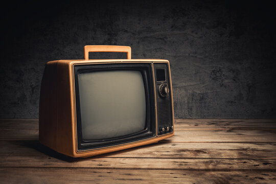 Vintage yellow old TV on wood table in the black room, close-up, side view