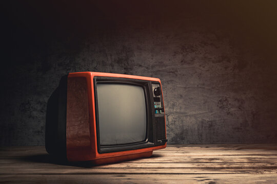 Vintage, still life retro red old TV blank screen on wood table in the black room, close-up, side view