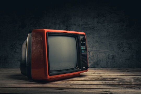 Vintage, still life retro red old TV blank screen on wood table in the black room, close-up, side view