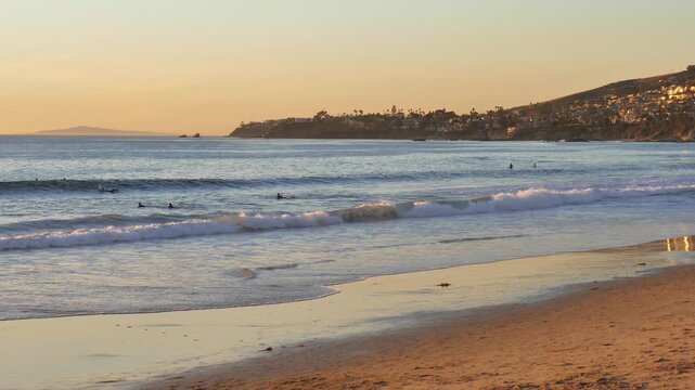 Looking south down the coast from Oak Street Beach at Laguna Beach, California during sunset. Surfers and swimmers in the water.