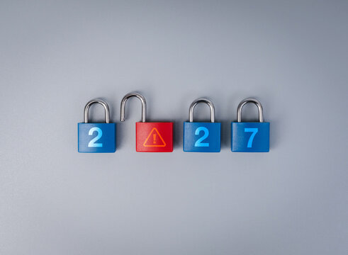 Locked blue padlocks surround open red warning lock with 2027 new year concept. Cybersecurity risk, data protection, digital vulnerabilities, compliance concerns and future security challenges.