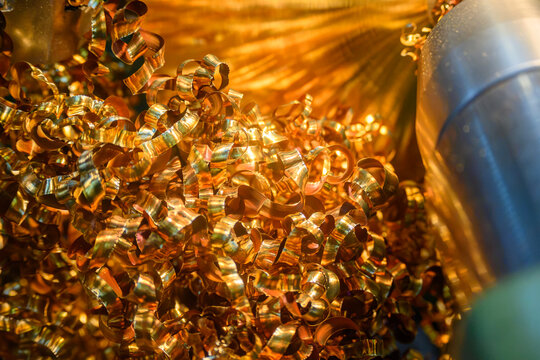Piles of continuous brass material chips from a turning process on a lathe machine