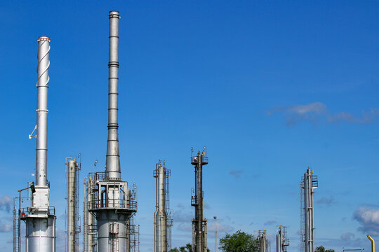 Industrial Refinery Columns and Metal Smokestacks Under Blue Sky