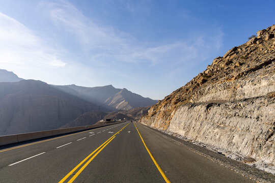 Scenic Road Through Rugged Mountain Cliffs, Blue Sky