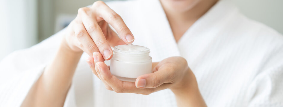 Health care, beauty asian young woman in bathrobe, towel after shower bath, spa relax at home, use finger putting take out moisturizer cream from jar. Skin body moisturizing lotion, routine in morning