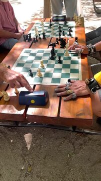 Ajedrez partida con jugadores y piezas en tablero anillos de plata y oro chess con reloj de tiempo y dedos de manos con amuletos talism&aacute;n