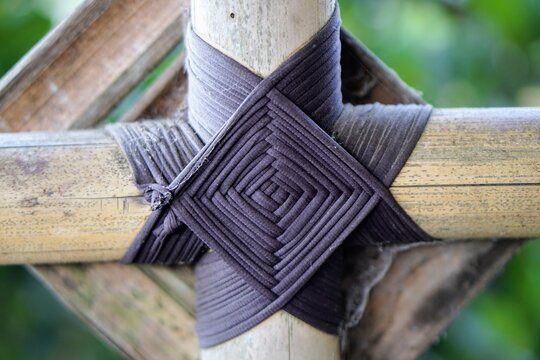Detail of a traditional black rope binding forming a neat diamond pattern on a bamboo cross joint.