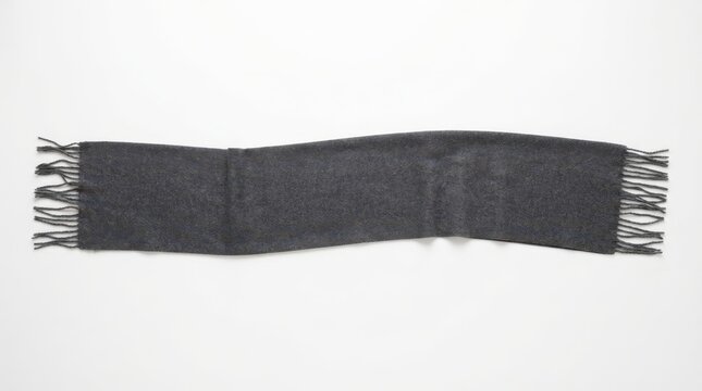 Folded dark grey wool scarf with fringe detail centered on a plain white surface for minimalist fashion product display