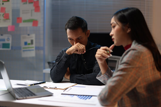 Stressed business team facing deadline and potential failure, working late in an office, experiencing stress and burnout from work.