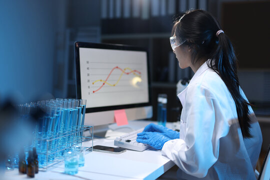 Asian scientist analyzing research data in laboratory, working on a computer observing experiment results.