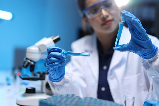 Scientist researching chemical liquid in test tube for analysis. Young scientist analyzing chemical liquid in test tube, conducting medical research and chemistry experiment in a laboratory.