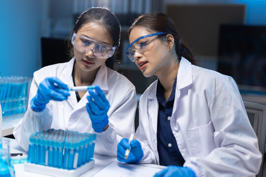 Woman scientists discussing experiment data in laboratory.