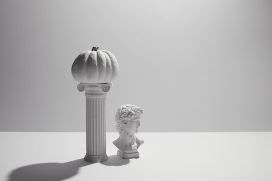 White pumpkin balancing on column with david bust