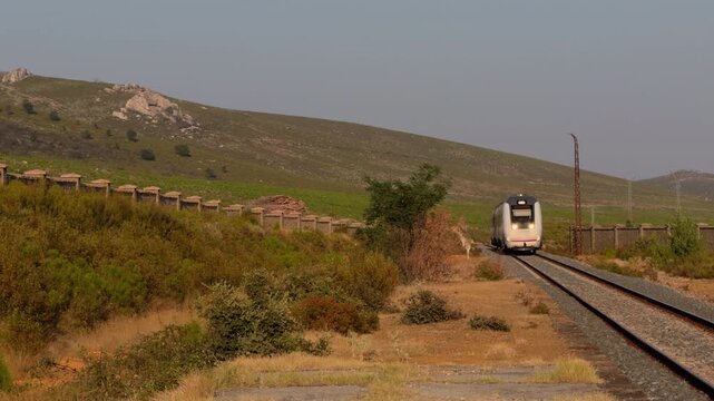 Passenger Train Approaching Through Dry Mountain Landscape