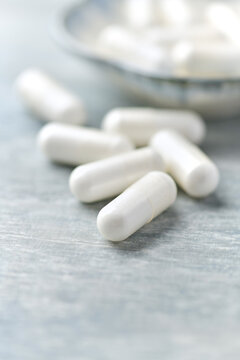 Creatine capsules on wooden background. Soft focus. Close up. Copy space