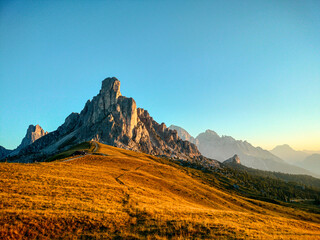Fototapeta premium Golden alpine meadow at sunset in Dolomites, Italy - Passo Giau