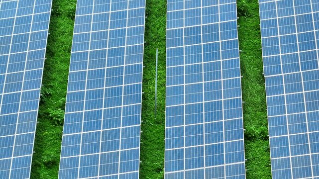 Aerial view reveals organized solar panels over green terrain, representing renewable electricity, environmental conservation, clean technology and a greener energy future for the modern world. 4k.

