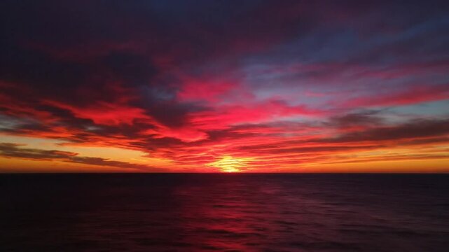 Mesmerizing time-lapse of a colorful sunset over the ocean, painting the sky with fiery hues and dramatic cloud formations