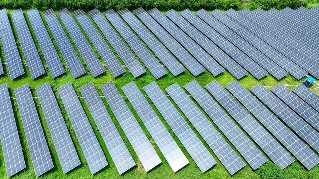 An aerial view of an expansive solar farm shows rows of photovoltaic panels integrated with green land, symbolizing clean technology, renewable electricity and a greener future for the modern world.
