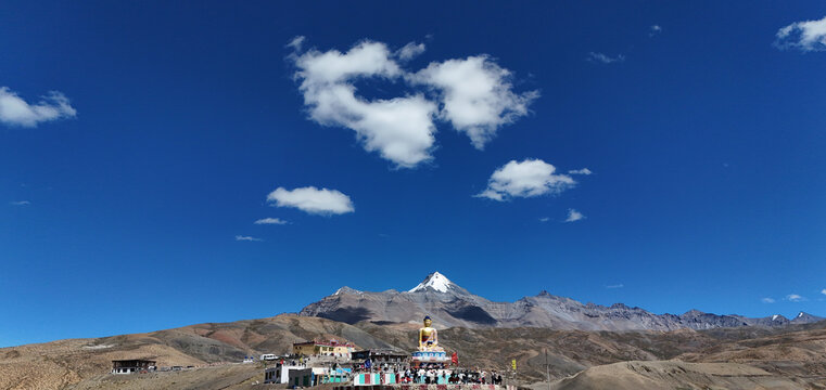 Beautiful Wide Aerial View of Langza Buddha Statue in Spiti Valley, Himachal Pradesh Surrounded by Barren Rocky Mountains and Vast Blue Himalayan Sky