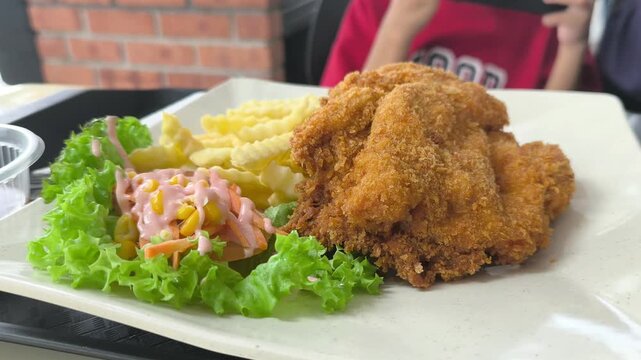 A delicious chicken chop is served on a clean white plate. The hot dish is plated beautifully and ready to be enjoyed.