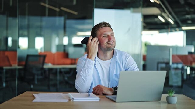 Businessman Smiling While Listening to Voice Message on Smartphone in Office