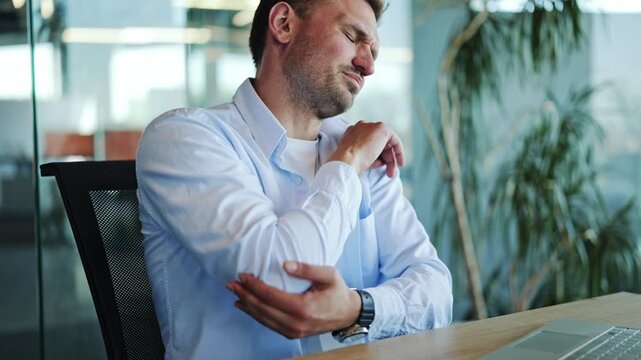 Office Worker in Light Blue Shirt Suffering From Elbow Pain at Desk