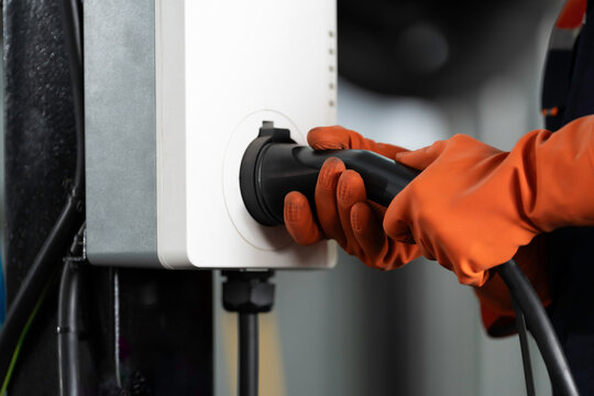 EV wall charger, Electric vehicle charging, Wall charger installation. Hands of technician install, checking, insert EV charging cable plug into station socket home EV charging station