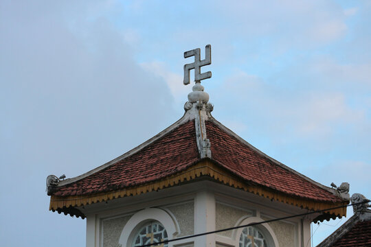 Traditional Buddhist swastika sign on ancient pagoda roof spire with copy space, oriental religious architecture background template for text