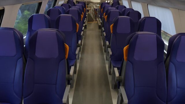 Empty blue passenger seats with yellow handles inside modern train carriage, showing travel