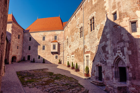 Sunlit inner courtyard wall and Gothic doorway at Corvin Castle in Hunedoara Romania